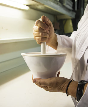 Scientist grinds up compound in porcelain mortar