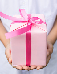 Young boy hand give pink gift box