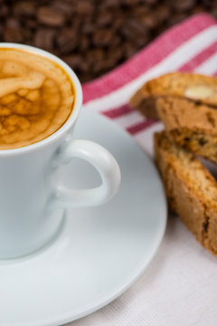 cup of creamy expresso over roasted coffee beans and italian bis