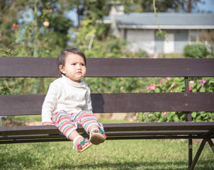 Cute baby girl sit on the bench in the park