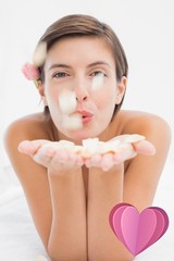 Beautiful happy woman blowing flower petals at spa center