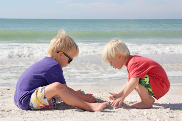 Two Young Children Playing in Sand on Beach by Ocean