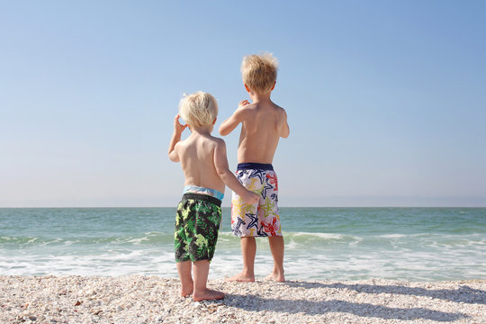 Two Young Children Looking Out Over Ocean on Beach