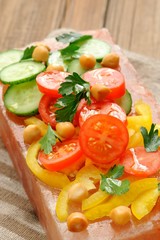 Vegetable salad on pink salt block on stripe napkin