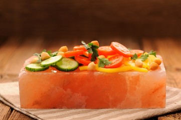 Vegetable salad on pink salt block on stripe napkin