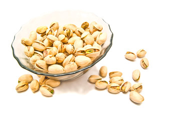 plate with tasty pistachios on white