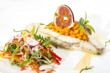 Baked fish with salad on a white background in restaurant