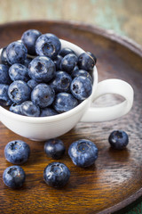 Blueberries in a cup on a wooden table.