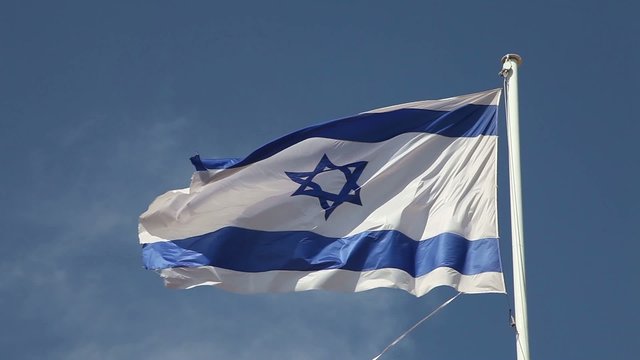 Israel flag waving in wind against blue sky
