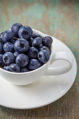 Blueberries in a cup on a wooden table.
