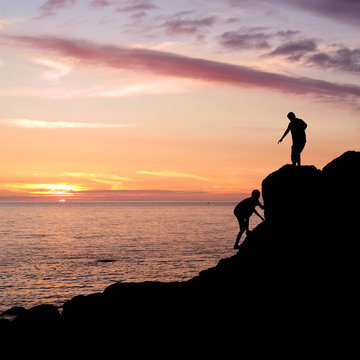 Climbing silhouettes at rocky seashore