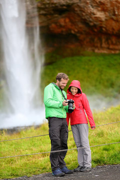 Tourists with SLR camera by waterfall on Iceland