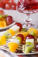 Fresh fruit on skewers and red wine close-up vertical