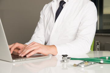 hands of doctor writing at computer