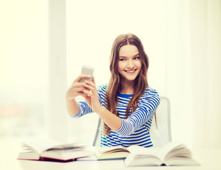 Fototapeta premium smiling student girl with smartphone and books