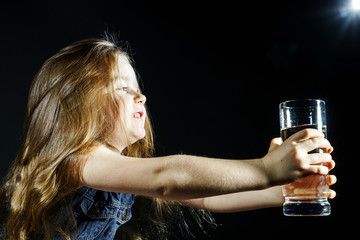 Cute little girl with long hair holding glass of water