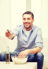 smiling man with tv remote control at home