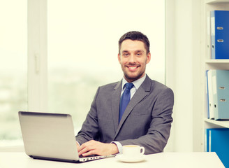 Fototapeta na wymiar smiling businessman with laptop and coffee