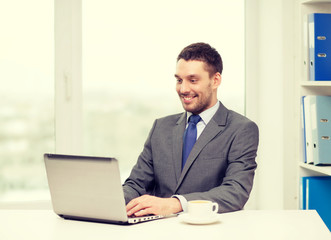 smiling businessman with laptop and coffee