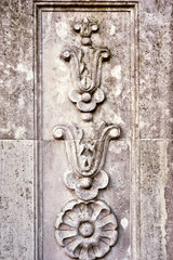 Ornamental floral curves on stone wall.