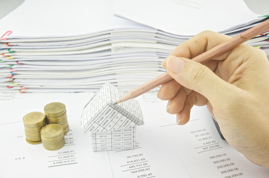 Man holding pencil over house on balance sheet