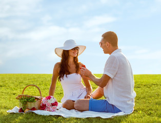 smiling couple with small red gift box on picnic