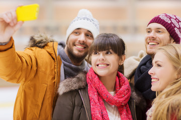 happy friends taking selfie on skating rink