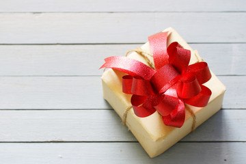 Brown gift box with red ribbon and paper sheet on wood table