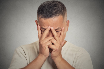 Young man with depressed face expression on grey background 