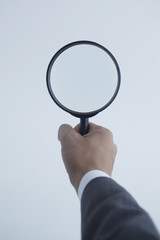 虫メガネを持つビジネスマンの手