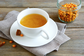 Sea-buckthorn tea in a cup on wooden boards
