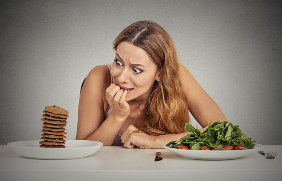 woman deciding to eat healthy food or sweet cookies she craving