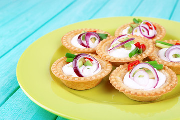 Tartlets with greens and vegetables with sauce on plate on