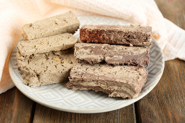 Two kinds of sunflower halva on plate, on wooden background