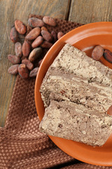Sunflower halva with cocoa on plate, on wooden background
