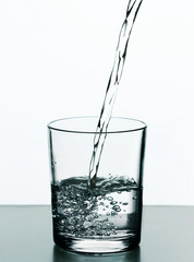 Pouring water from bottle on  glass isolated on white