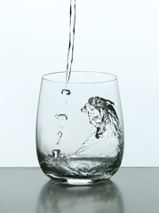Pouring water from bottle on  glass isolated on white