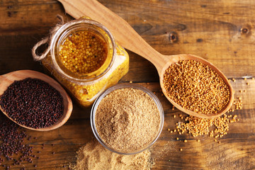 Mustard seeds, powder and sauce in glass jar, bowl and wooden