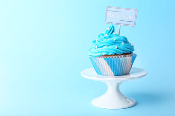 Delicious cupcake with inscription on blue background