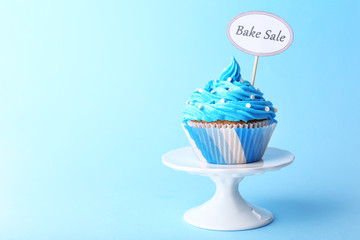 Delicious cupcake with inscription on blue background