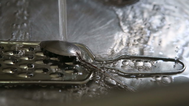 grater spoon and fork in the sink to wash under running water	