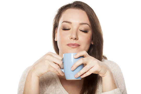 positive young woman enjoying the scent of a cup of tea