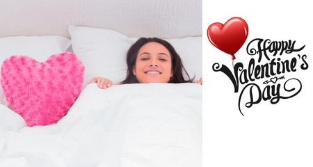Woman lying in bed next to a fluffy heart pillow