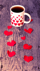 Valentine hearts and cup of tea on the old wooden table. Toned