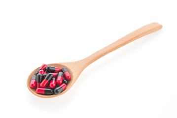 Pills drug on wooden spoon isolated on white background