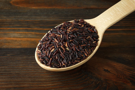 Black rice in a wooden spoon on wood