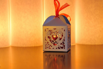 Decorative box with a heart cutout lit by a glowing candle with
