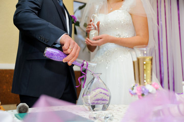hands of bride and groom doing sand ceremony during wedding