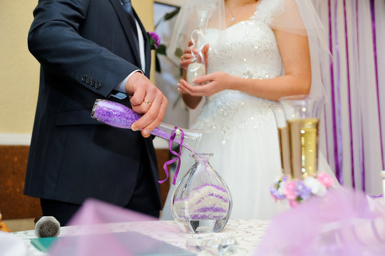 hands of bride and groom doing sand ceremony during wedding