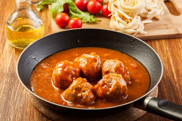 Meatballs with tomato sauce on black pan